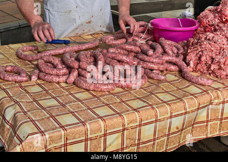 Il macellaio rende salsicce fatte in casa all'aperto in un modo tradizionale. Foto Stock