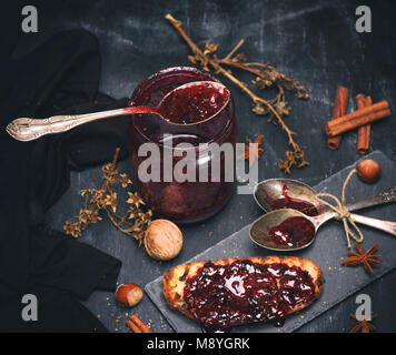 Confettura di lamponi in un vasetto di vetro con un cucchiaio di ferro, tonificazione vintage Foto Stock