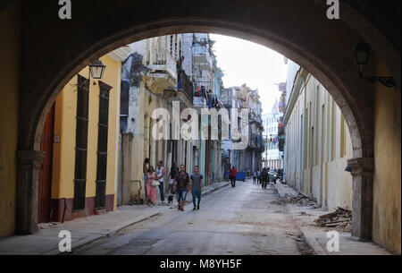 La gente a piedi lungo una strada fiancheggiata con i suoi edifici colorati verso un arco nella Vecchia Havana, Cuba. Foto Stock