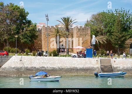 Vista l'arco d'ingresso dei governatori Castello (Castelo dos Governadores) con piccole imbarcazioni ormeggiate in primo piano e turisti che si godono la frassineti Foto Stock