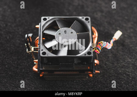 CPU platina di calore da un PC. Heatsinker di rame con una ventola di raffreddamento del processore. Isolato su uno sfondo scuro. Vista dall'alto. Foto Stock