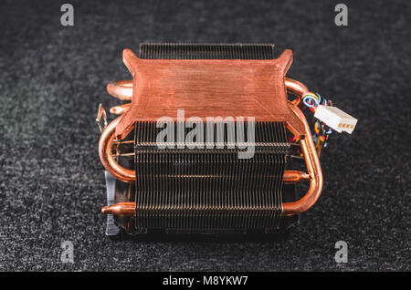 CPU platina di calore da un PC. Heatsinker di rame con una ventola di raffreddamento del processore. Isolato su uno sfondo scuro. Vista dal basso. Foto Stock