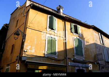 Scena di strada in Arles, giallo casa tradizionale con persiane verdi e ristorante vintage segno, Provenza, Francia Foto Stock