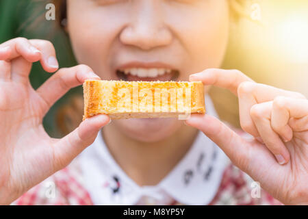 Carino donne che detenga burro toast di mangiare la mattina closeup Foto Stock