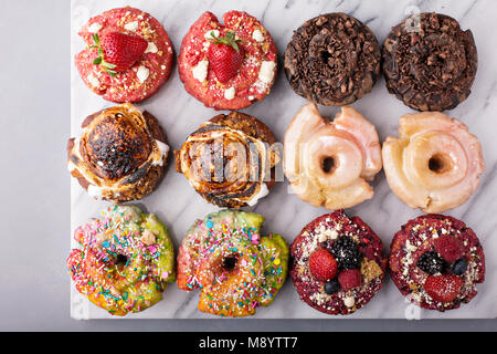 Varietà di ciambelle su un piano di marmo Foto Stock