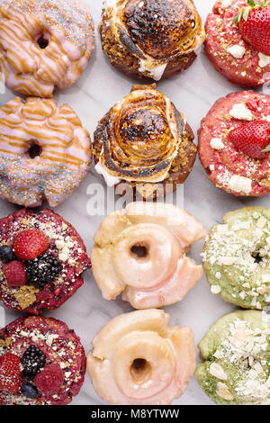 Varietà di ciambelle su un piano di marmo Foto Stock