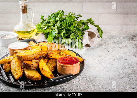 Cotta patate fritte con aglio, erbe, il bianco e il rosso salse, sulla pietra grigia sfondo spazio di copia Foto Stock