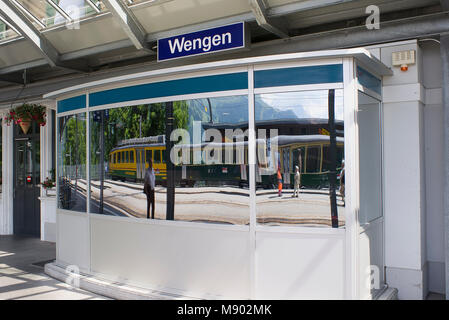 Riflessioni di un mouintain convoglio ferroviario nella stazione ferroviaria di Wengen in Svizzera Foto Stock