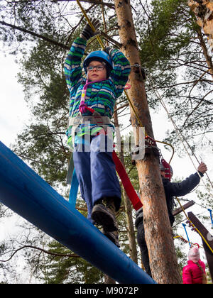 Sosnovy Bor, Russia - Marzo 19, 2016: Boy camminando su un registro su un sospesi nelle classi del club turistico Foto Stock