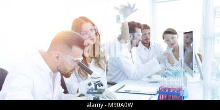 Gli scienziati di esaminare attentamente la pipetta con fluido blu in laboratorio..foto con spazio di copia Foto Stock