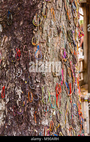 Braccialetti colorati a sinistra dai visitatori in corrispondenza di un albero utilizzato dal Khymer Rouge al club i neonati e i bambini a morte, Choeung Ek Killing Fields genocidio centro, Phnom Penh, Cambogia, sito in cui decine di migliaia di persone in Cambogia sono stati uccisi dalla Khymer Rouge sotto gli ordini di Pol Pot da 1975-1979. Foto Stock