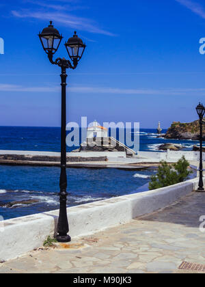 Piccoli semafori sulla strada nei pressi del porto, con una piccola cappella e il faro bianco in background Foto Stock