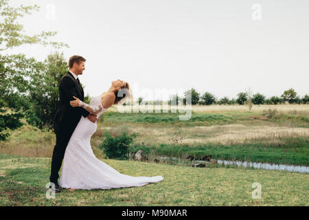 Per tutta la lunghezza della sposa giovane in piedi insieme in un parco. Sposa e lo sposo prima della cerimonia nuziale. Foto Stock