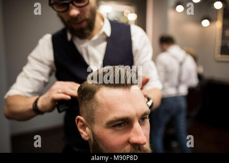 Ritagliato ritratto di barbiere per lo styling dei capelli del cliente Foto Stock