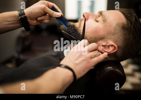 Profilo Ritratto di giovane uomo con barba tagliati a Barbiere Salone di bellezza Foto Stock