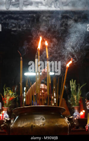 Il tempio taoista. L'imperatore Jade pagoda (Chua Phuoc Hai). Adoratore buddista. La masterizzazione di bastoncini di incenso. Ho Chi Minh city. Il Vietnam. Foto Stock