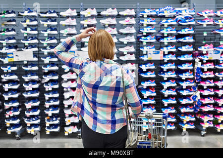 La donna decide di sneakers in uno sport negozio di abbigliamento Foto Stock