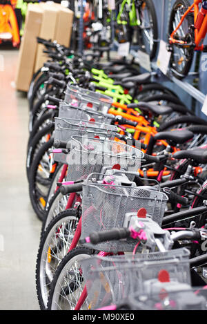 Fila di nuove biciclette con carrelli per gli acquisti nel negozio di sport Foto Stock