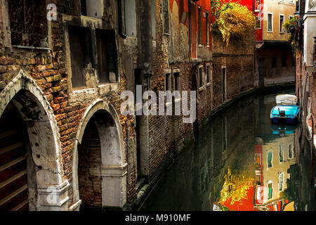 Stretto canale ombreggiato percorso di decadimento vecchi muri di mattoni evoluzione del fogliame soleggiato riflettendo in acqua e pitturato di bianco arcate e cenge in Venezia Foto Stock