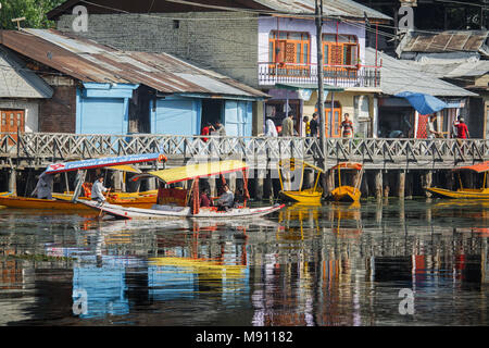 Shikara imbarcazioni da diporto su Dal lago nella città di Srinagar Kashmir. Un reportage vivace scena con case di lakeside, passeggiata in legno e riflessione di acqua Foto Stock