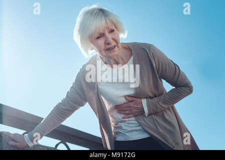 Spaventata signora anziana che soffre di un attacco di cuore Foto Stock