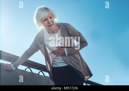 Frightened senior donna avente un attacco di cuore all'aperto Foto Stock