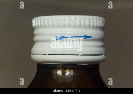 Foto macro di una bottiglia scura con la medicina e un coperchio bianco. Freccia blu sul lato del coperchio. Il sito di medicina e salute. Foto Stock