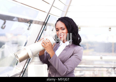 Ritratto di un felice imprenditrice guardando attraverso il binocolo cityscape Foto Stock