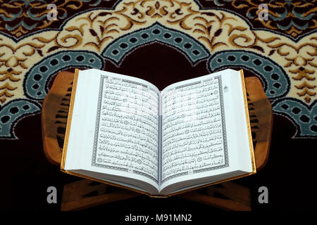 Un open Santo Corano su piedistallo in legno. Foto Stock