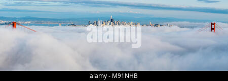 Vista di Golden Bay Bridge coperto di dense nubi con il centro cittadino di San Francisco in centro Foto Stock