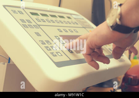 Il radiologo che preme il pulsante del pannello di controllo per produrre un'immagine a raggi x. Foto Stock