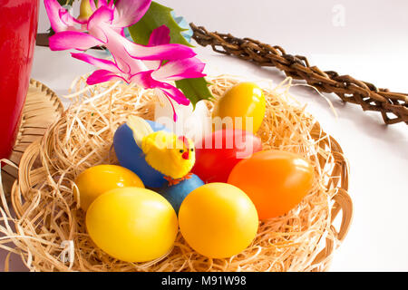 Decorazioni di pasqua. Nel cesto di vimini è una gallina con uova colorate nella covata. In fondo è il fiore del cactus di pasqua. Foto Stock