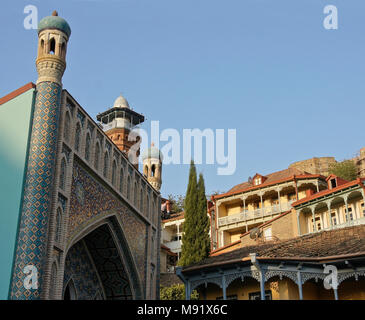 Il blue-facciata con piastrelle di bagni Orbeliani, rosso-mattone minareto della moschea, balconied case nella città vecchia e la fortezza di Narikala sulla collina, Tbilisi, Georgia Foto Stock