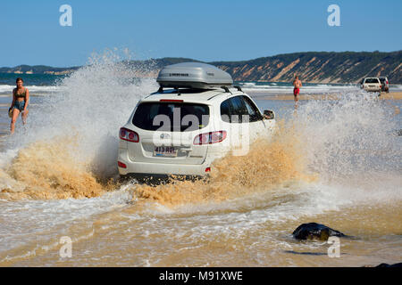 Rainbow Beach, Queensland, Australia - 23 dicembre 2017. 4WD Hyundai car guida attraverso un washout in schizzi di acqua oceanica su Rainbow Beach in Quee Foto Stock