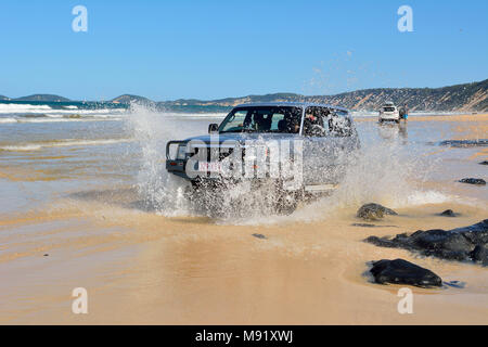 Rainbow Beach, Queensland, Australia - 23 dicembre 2017. 4WD auto Toyota la guida attraverso un washout in schizzi di acqua oceanica su Rainbow Beach in Queen Foto Stock