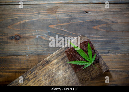 Foglia di marijuana su un brownie marijuana sul tavolo di legno Foto Stock