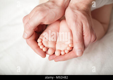 Piccolo neonato i piedi in mano maschio Foto Stock