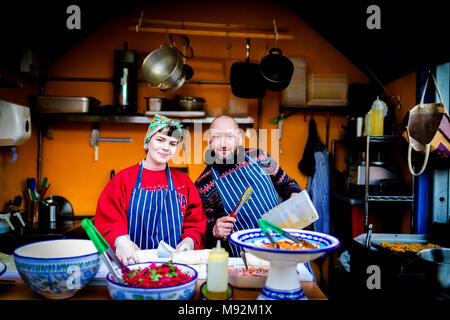 Il Caos, York il 16 febbraio 2018. La donna in una testa sciarpa e maschile chef in un grembiule su un cibo caldo stand, in stallo o in cucina in posa per la fotocamera Foto Stock