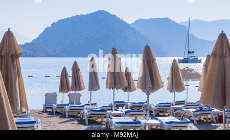 Ripiegate ombrelloni in Icmeler sullo sfondo di montagne e il mare Foto Stock