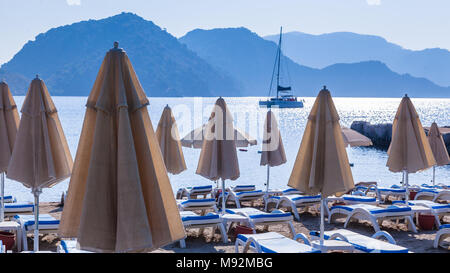 Ripiegate ombrelloni in Icmeler sullo sfondo di montagne e il mare Foto Stock