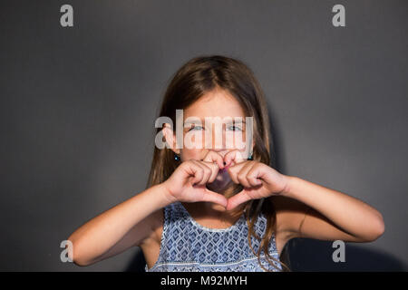 Bambina che mostra il cuore con le mani Foto Stock