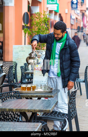 L'uomo versando marocchino tè alla menta da una pentola di metallo in strada, Marrakech, Marocco Foto Stock