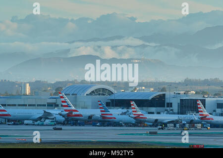 La mattina presto presso l'Aeroporto Internazionale di Los Angeles LAX. Parcheggiato American Airlines piani. Il segno di Hollywood, dietro, illuminata dal sole nascente. Foto Stock
