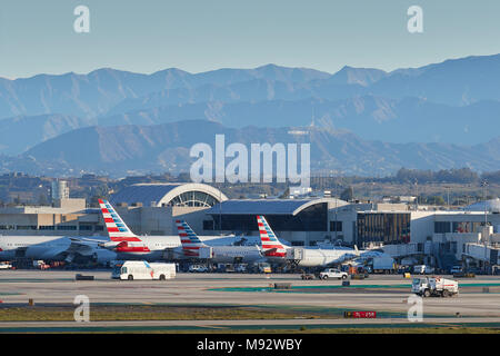 Parcheggiato American Airlines getti di passeggeri nelle prime ore del mattino presso l'Aeroporto Internazionale di Los Angeles LAX. Il segno di Hollywood e le montagne dietro. Foto Stock