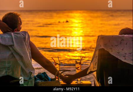 Vista sul giovane godersi il tramonto con cocktail su Koh Kood beach in Thailandia Foto Stock