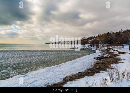 Scena invernale con scogliere crinali innevati con gelide acque del lago in un giorno nuvoloso Foto Stock