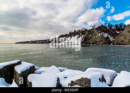 Scena invernale con scogliere crinali innevati con gelide acque del lago in un giorno nuvoloso Foto Stock