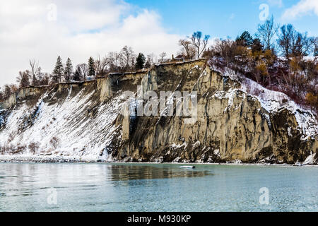 Scena invernale con scogliere crinali innevati con gelide acque del lago in un giorno nuvoloso Foto Stock