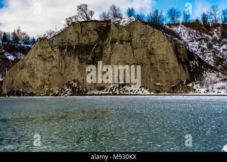 Scena invernale con scogliere crinali innevati con gelide acque del lago in un giorno nuvoloso Foto Stock