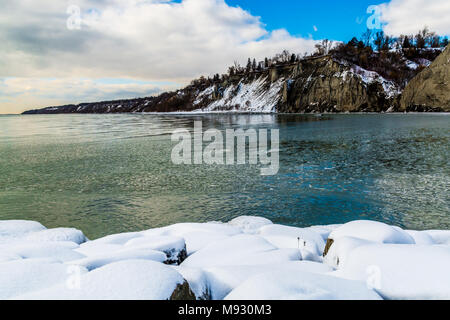 Scena invernale con scogliere crinali innevati con gelide acque del lago in un giorno nuvoloso Foto Stock